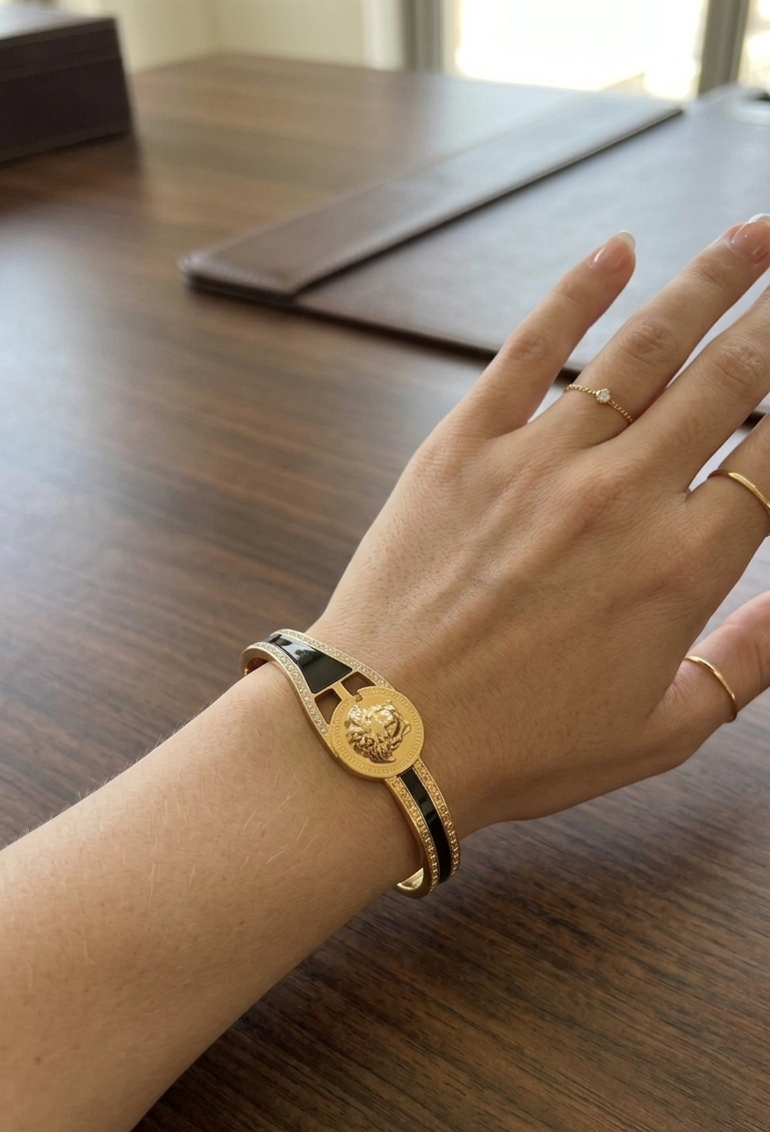 Hand wearing a gold bracelet on a wooden surface